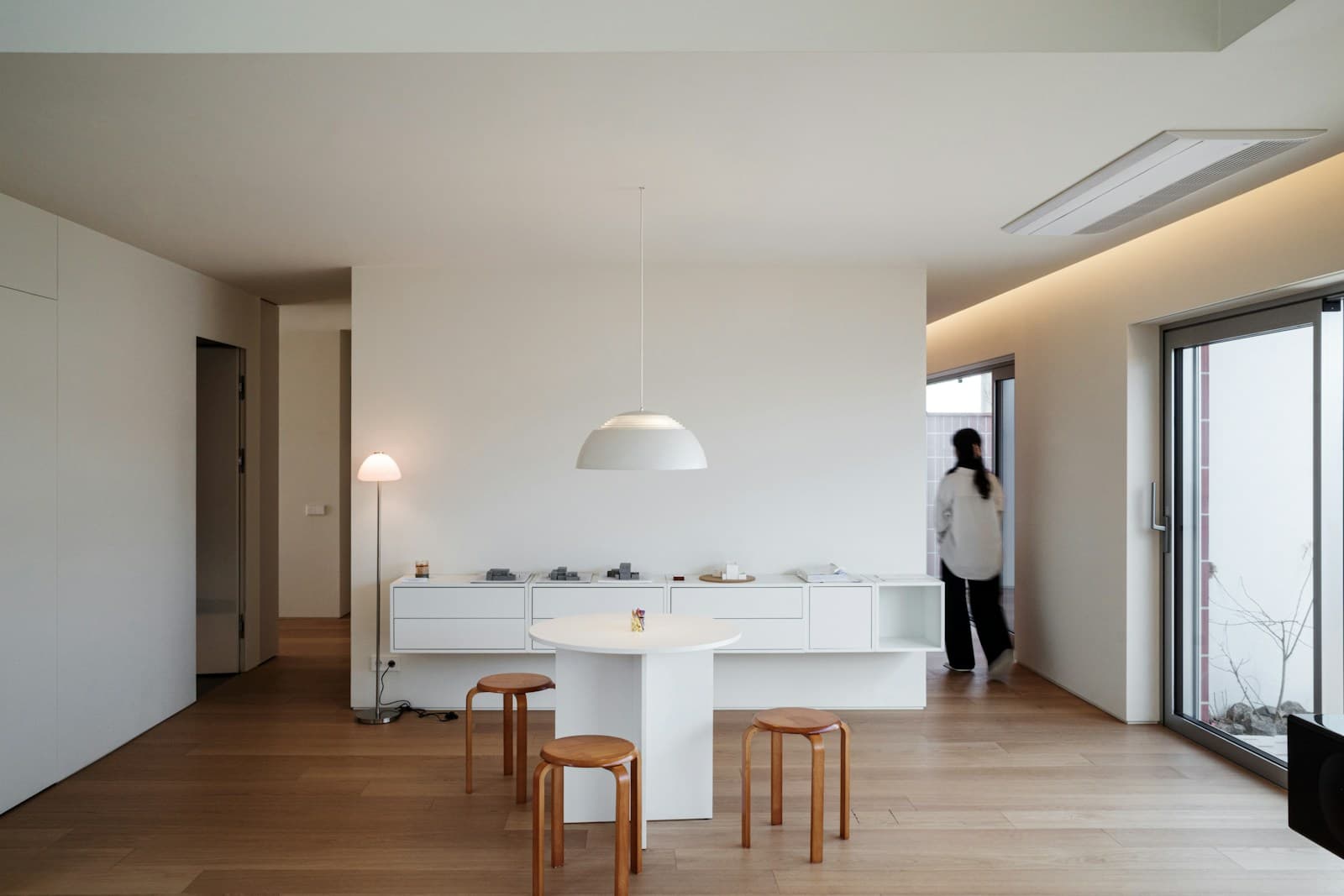Interior minimalis dengan meja putih, bangku kayu, dan cahaya natural